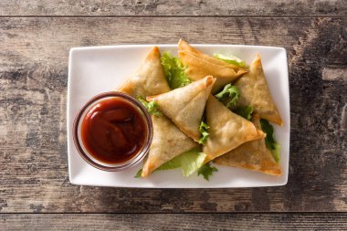 Samsa veya samosas ahşap masada et ve sebze ile. Geleneksel Hint yemekleri. Üstte görüntü.