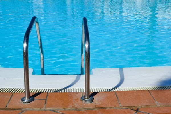 Swimming pool with grab bars ladder background. Summer concept.