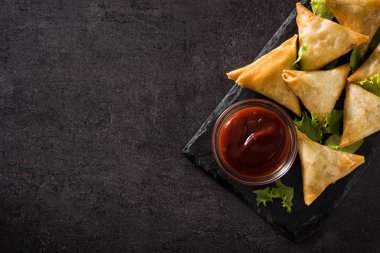 Samsa ya da siyah arka planda et ve sebze ile samosas. Geleneksel Hint yemekleri. Üst görünüm. Boşaltmak