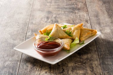 Ahşap arka planda et ve sebzelerle samsa veya samosas. Geleneksel Hint yemekleri. 