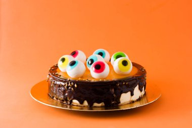 Turuncu arka plan üzerinde şeker gözleri dekorasyon ile Halloween pasta. 