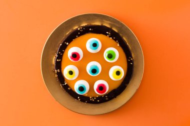 Turuncu arka plan üzerinde şeker gözleri dekorasyon ile Halloween pasta. Üstte görüntü.  