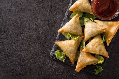 Samsa ya da siyah arka planda et ve sebze ile samosas. Geleneksel Hint yemekleri. Üst görünüm. Boşaltmak