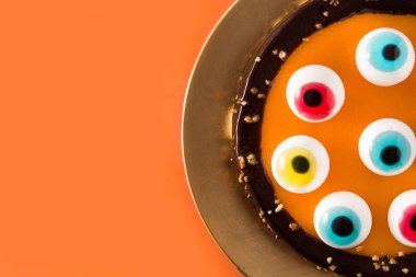 Turuncu arka plan üzerinde şeker gözleri dekorasyon ile Halloween pasta. Üst te. Copyspace