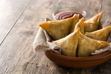 Samsa veya samosas ahşap masada kase içinde et ve sebze ile. Geleneksel Hint yemekleri. Copysace