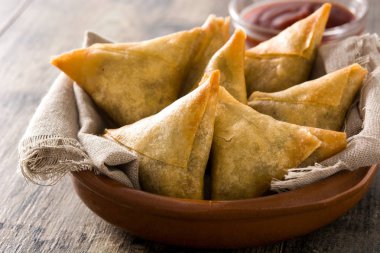 Samsa veya samosas ahşap masada kase içinde et ve sebze ile. Geleneksel Hint yemekleri