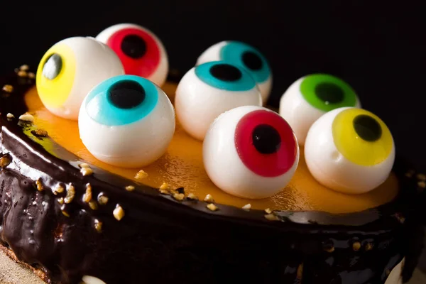 Halloween cake with candy eyes decoration on wooden table. Close up