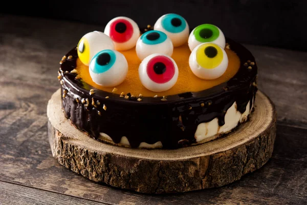 Halloween cake with candy eyes decoration on wooden table.