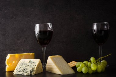 Siyah arka planda peynir ve şarap çeşitleri. 