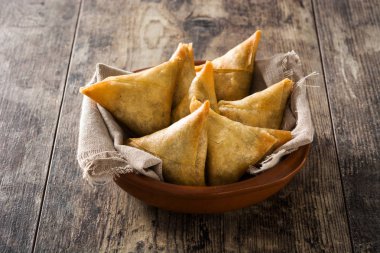 Samsa veya samosas ahşap masada kase içinde et ve sebze ile. Geleneksel Hint yemekleri