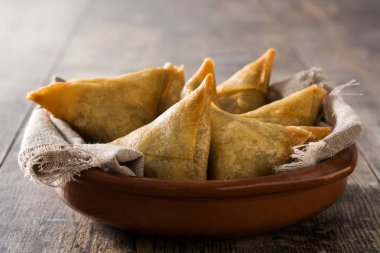 Samsa veya samosas ahşap masada kase içinde et ve sebze ile. Geleneksel Hint yemekleri