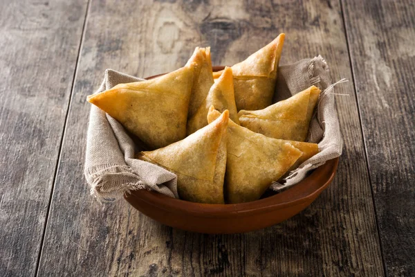 Samsa veya samosas ahşap masada kase içinde et ve sebze ile. Geleneksel Hint yemekleri