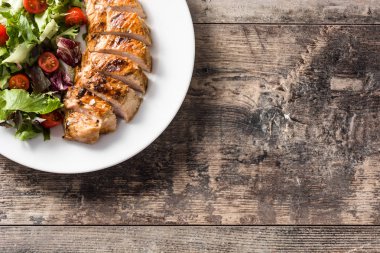 Ahşap masa üzerinde bir tabak üzerinde sebze ile ızgara tavuk göğsü. Üst te. Kopyalama alanı