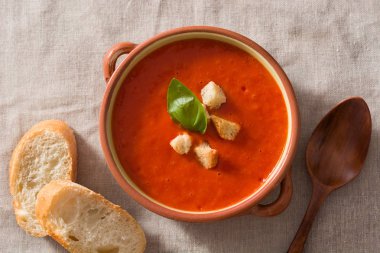 Tahta masa üzerinde kahverengi kase domates çorbası. Üstte görüntü