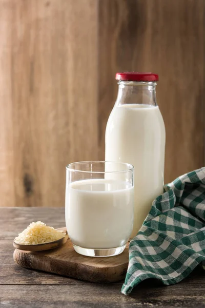 Rice milk in glass and bottle on wooden table.