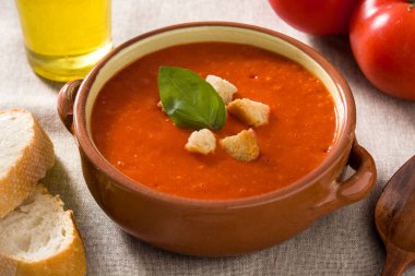 Kahverengi kâsede kıtır ekmekle süslenmiş domates çorbası.