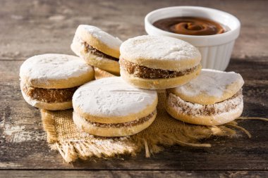Geleneksel Arjantin alfajorleri. Dulce de leche ve ahşap masa üzerinde şeker.