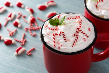 Mavi arka planda Noel için şeker kamışlarıyla süslenmiş nane şekerli kahve. Boşluğu kopyala