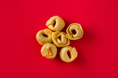 Fresh tortellini pasta isolated on red background