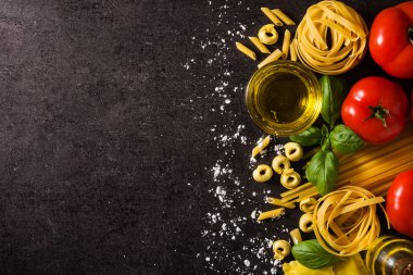 İtalyan makarnası ve malzemeleri. Ravioli, makarna, spagetti, tortellini, domates ve siyah arka planda fesleğen. Üst görünüm kopyalama alanı