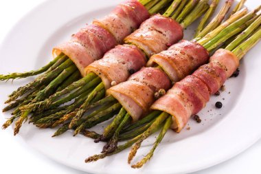 Beyaz arka planda izole edilmiş pastırmayla sarılmış yeşil kuşkonmaz.