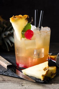 Soğuk mai tai kokteyli, ananas ve kirazlı ahşap masada.