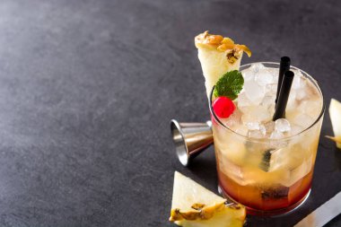 Siyah arka planda ananas ve kirazlı soğuk mai tai kokteyli. Boşluğu kopyala