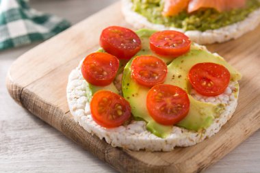 Domatesli pirinç keki ve ahşap masada avokado.