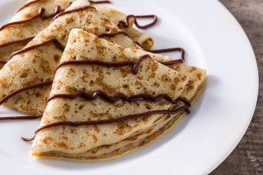 Tahta masadaki çikolatalı tatlı krepler. Yaklaş.