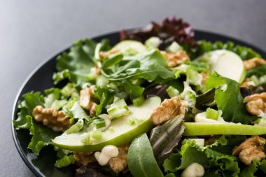 Marullu taze Waldorf salatası, yeşil elma, ceviz ve gri taş zemin üzerinde kereviz.