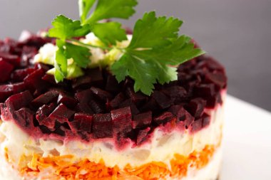 Siyah arka planda pancar ve havuçlu geleneksel Rus ringa salatası.