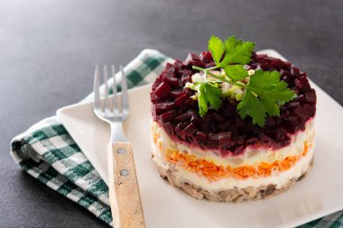 Siyah arka planda pancar ve havuçlu geleneksel Rus ringa salatası.