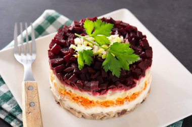 Siyah arka planda pancar ve havuçlu geleneksel Rus ringa salatası.