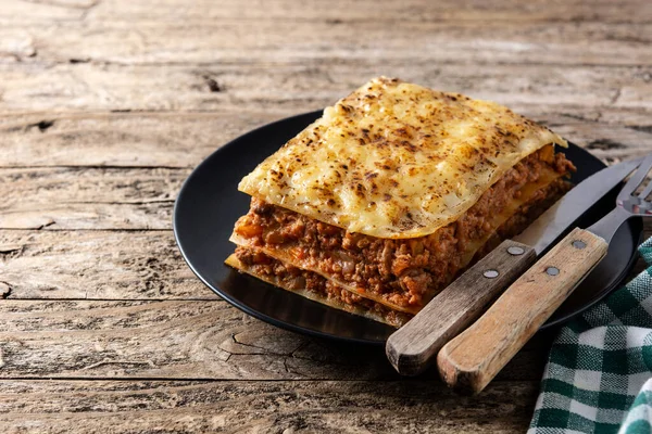 Trozo Lasaña Carne Plato Negro Sobre Una Mesa Madera Rústica —  Fotos de Stock