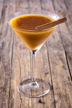 Ahşap masada cam içinde balkabağı kokteyli.