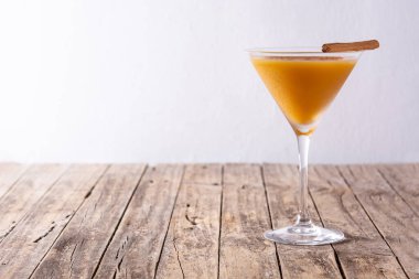 Ahşap masada cam içinde balkabağı kokteyli. Boşluğu kopyala