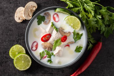 Geleneksel Tayland yemekleri Tom Kha Gai hindistan cevizi sütü çorbası tavuk, zencefil, biber, limon ve siyah arka planda mantar.