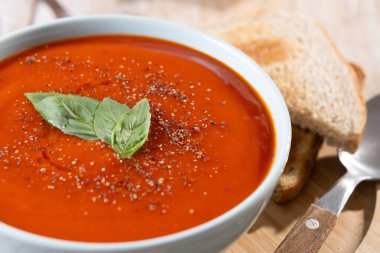 Ev yapımı domates çorbası ve ahşap masada fesleğen. Kapat.