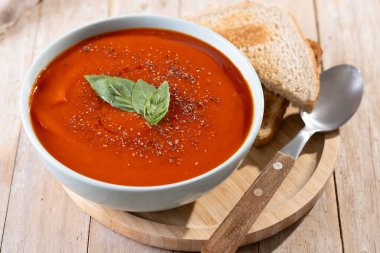 Ev yapımı domates çorbası ve ahşap masada fesleğen.