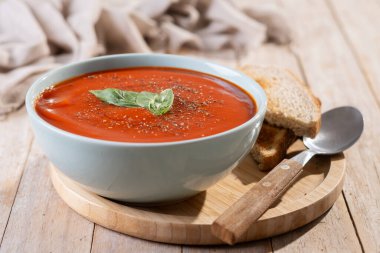 Ev yapımı domates çorbası ve ahşap masada fesleğen.