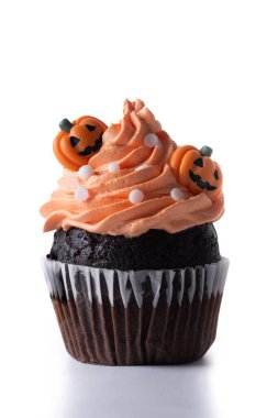 Beyaz arka planda turuncu tereyağlı ve balkabağı süslemeli Cadılar Bayramı kekleri