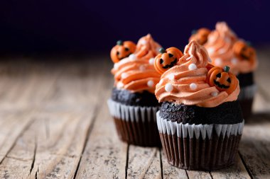 Köylü ahşap masasında balkabağı süslemeli Cadılar Bayramı kekleri ve siyah arka plan. Boşluğu kopyala