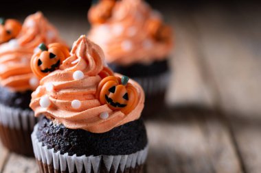 Köylü ahşap masasında balkabağı süslemeli Cadılar Bayramı kekleri ve siyah arka plan. Boşluğu kopyala