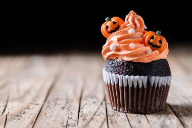 Köylü ahşap masasında balkabağı süslemeli Cadılar Bayramı kekleri ve siyah arka plan. Boşluğu kopyala