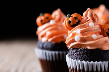 Köylü ahşap masasında balkabağı süslemeli Cadılar Bayramı kekleri ve siyah arka plan. Boşluğu kopyala