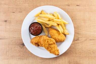 Tahta masada kızarmış patates kızartması ve kızarmış tavuk.