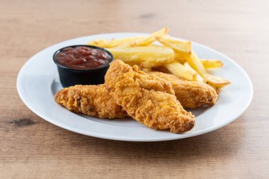 Tahta masada kızarmış patates kızartması ve kızarmış tavuk.