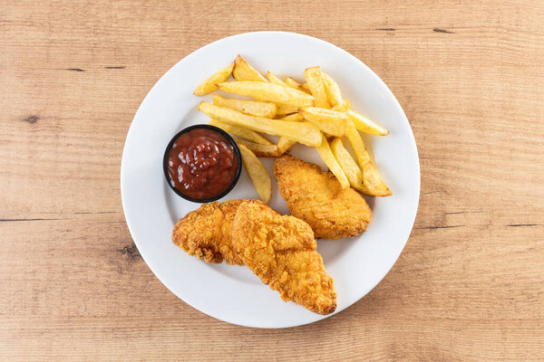 Хрустящие куриные тендеры с картошкой фри на деревянном столе