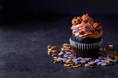 Siyah yüzey ve mor arka planda balkabağı süslemeli Cadılar Bayramı çörekleri. Boşluğu kopyala