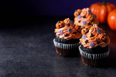 Cadılar Bayramı kekleri üzerinde siyah yüzey ve mor arkaplan parçacıkları var. Boşluğu kopyala